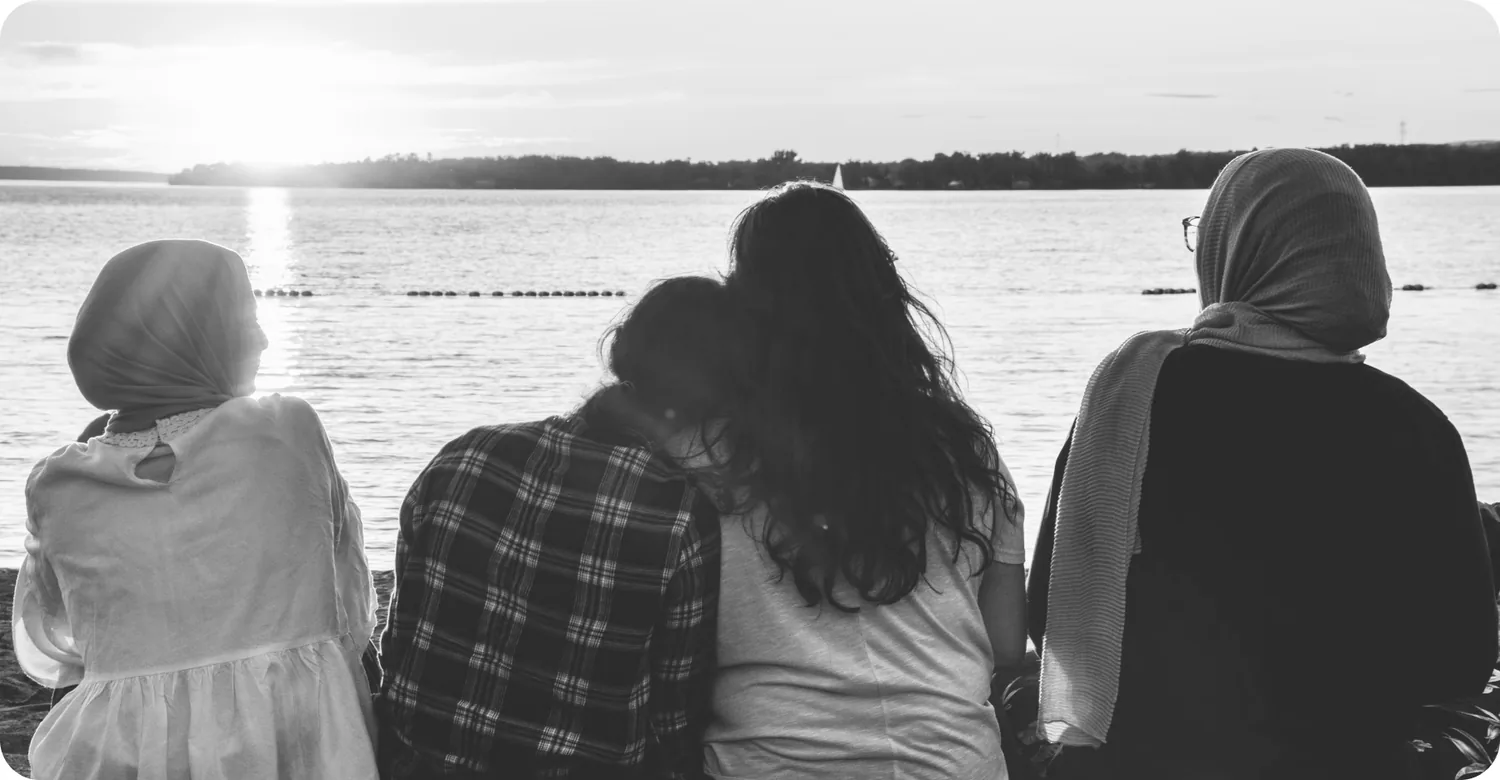 Four women sitting together looking out over water